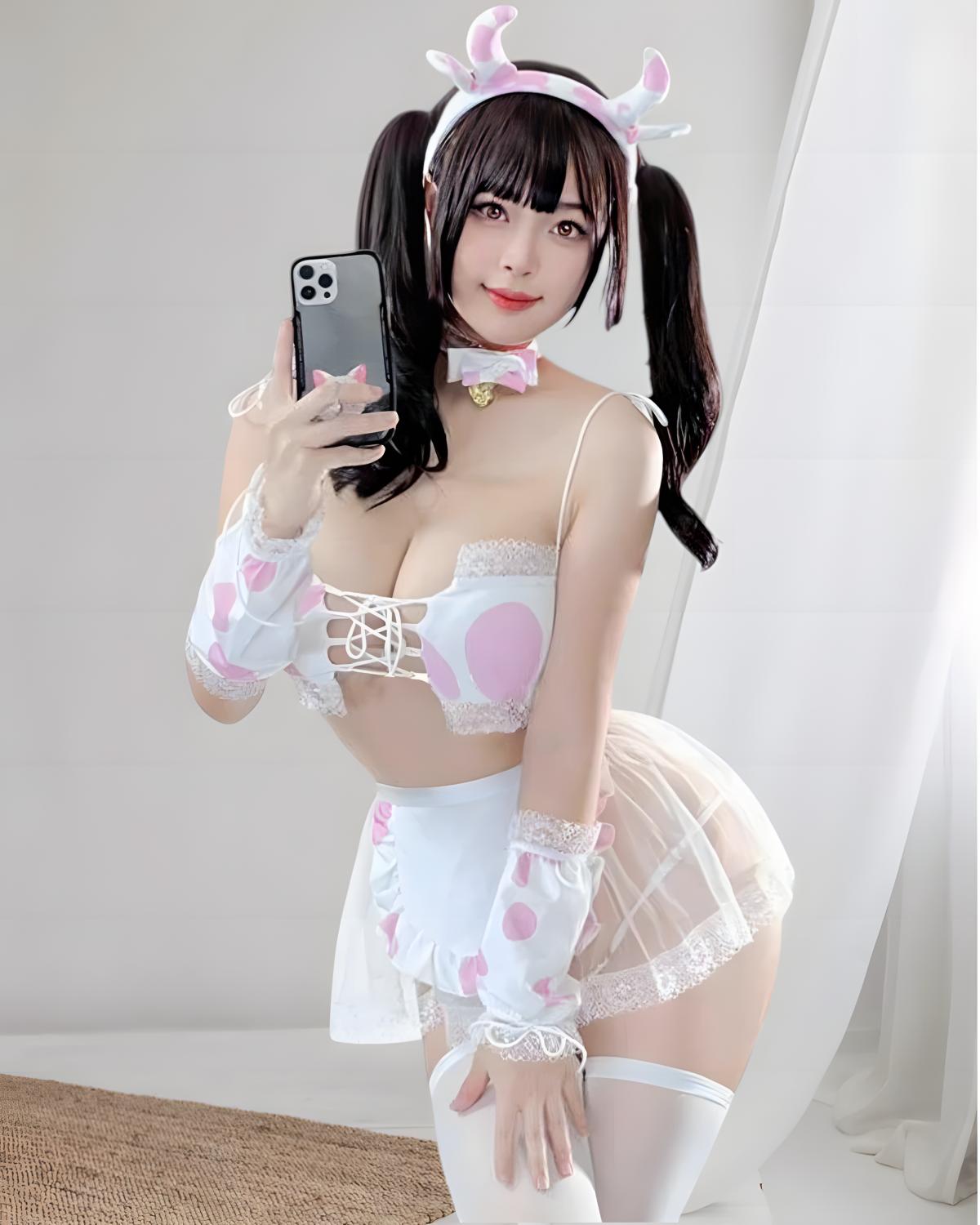 Person wearing a maid outfit with pink accents, taking a selfie.