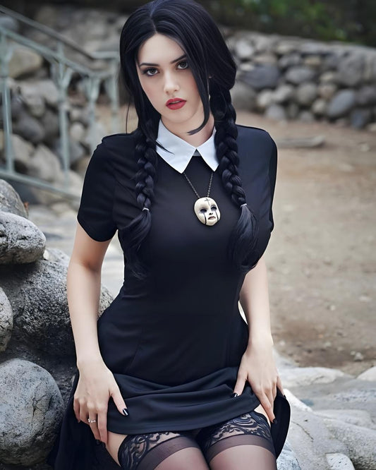 Woman in a black dress with braided hair sitting outdoors on rocks.