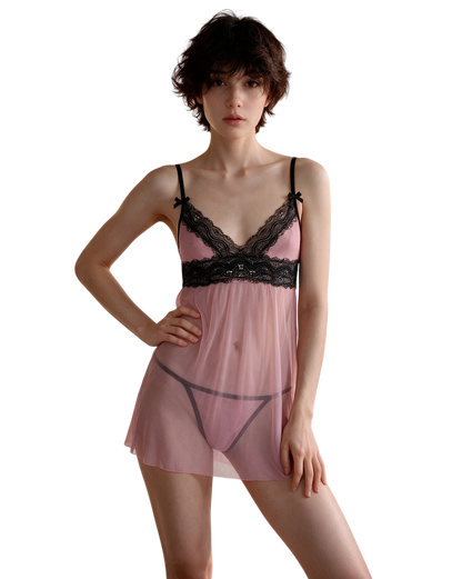 A model wearing a sheer pink babydoll lingerie chemise with black lace trim and black undergarments, set against a plain white background.