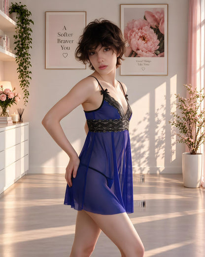 A woman models a sheer royal blue babydoll lingerie dress with black lace trim in a brightly lit, modern bedroom setting.