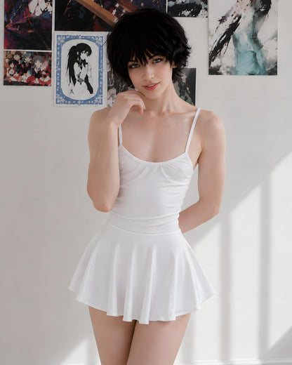 A woman modeling a white spaghetti-strap mini dress with a flared skirt, standing against a white wall decorated with anime posters.