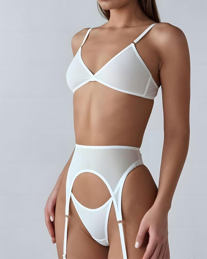 A model wearing a white lingerie set consisting of a triangle bralette and matching high-waisted garter belt with thigh straps, photographed against a light gray studio background.