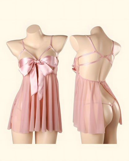 A pink sheer babydoll lingerie chemise shown on two mannequins, one facing forward with a large satin bow at the bust and one facing backward to show the open back and strappy design, against a plain cream background.