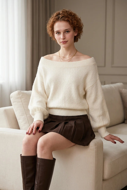 Ivory fuzzy sweater styled with a brown pleated skirt in a seated front view