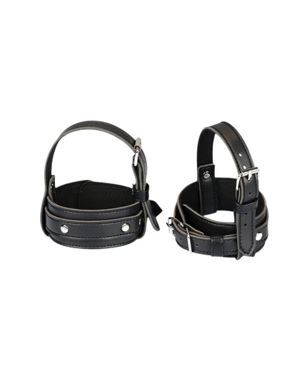 Two black leather restraint cuffs with silver metal buckles and rivets, displayed side-by-side on a plain white background.