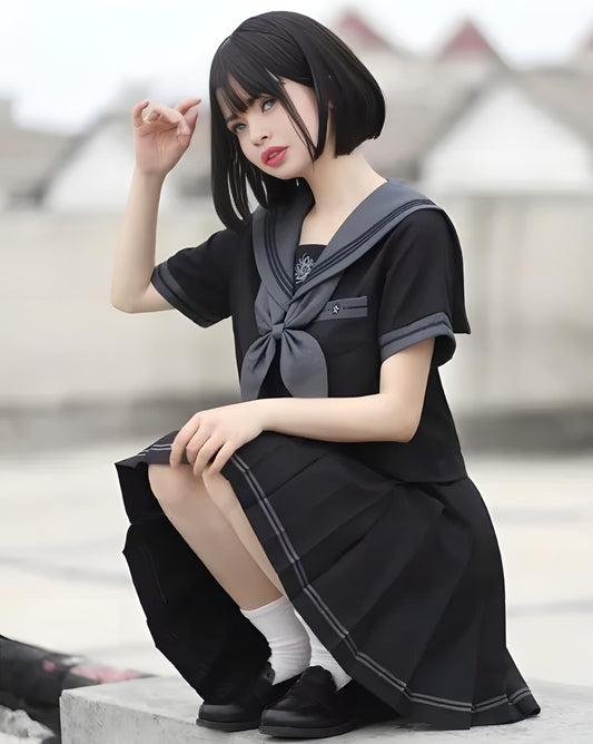 Person wearing a black and gray school uniform sitting on a concrete surface.