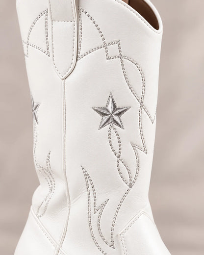 Close-up detail of star embroidery and contrast stitching on a white Western boot