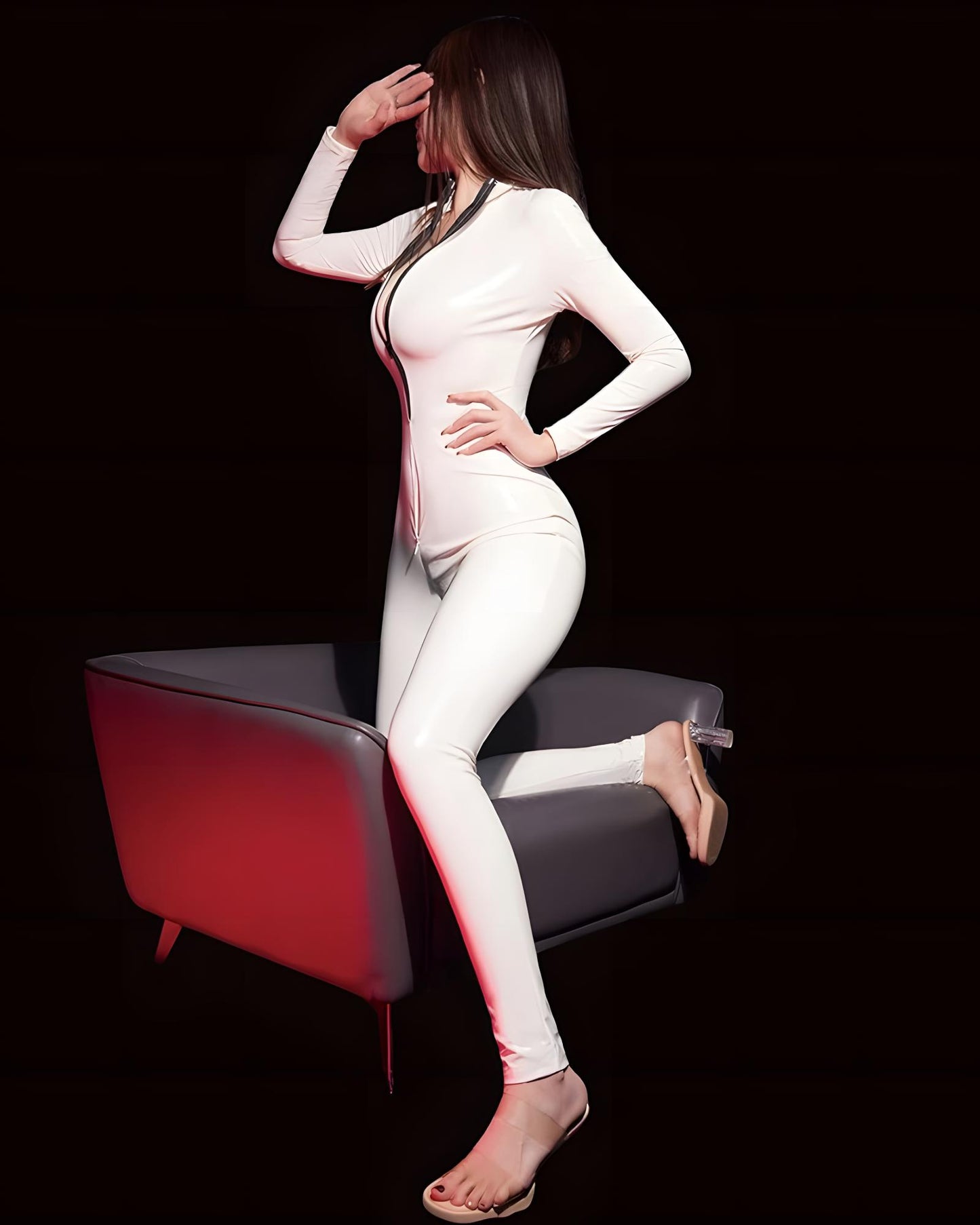 Woman in a white bodysuit sitting on a black chair with red accents against a black background