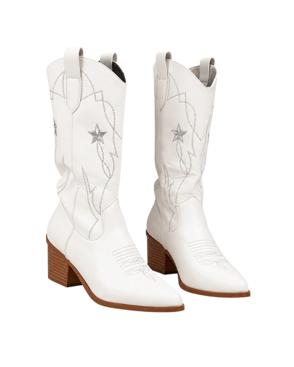 A pair of white leather cowboy boots with silver embroidered western patterns and star details, featuring brown stacked block heels, shown against a plain white background.