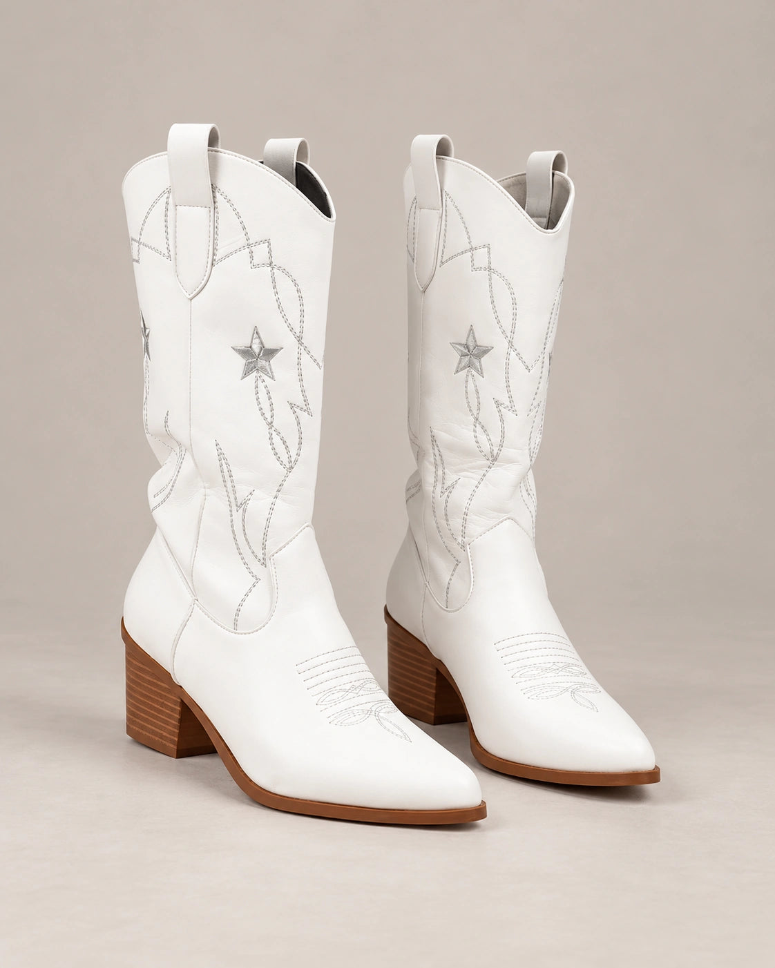 Angled view of white Western boots showing pointed toes, star stitching and block heels